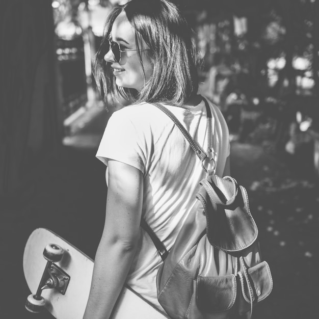 Frau, die draußen skateboard grayscale hält