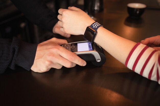 Frau, die durch Smartwatch mit NFC-Technologie bezahlt