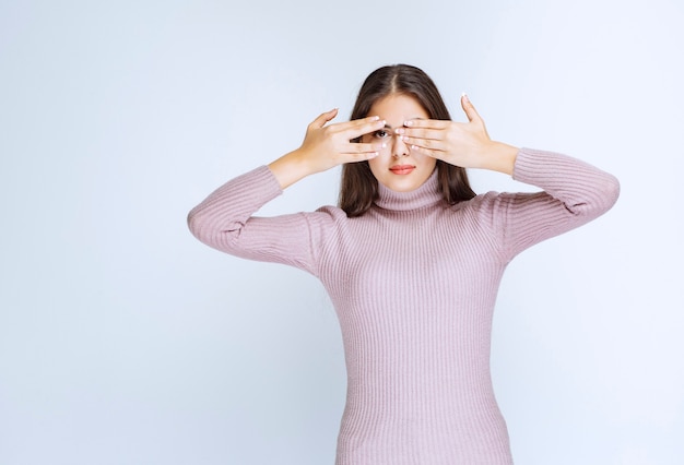 Frau, die ein Auge bedeckt und mit einem anderen über ihre Finger schaut.