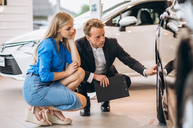 Frau, die ein Auto in einem Autosalon wählt