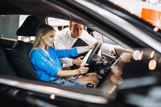 Frau, die ein Auto in einem Autosalon wählt