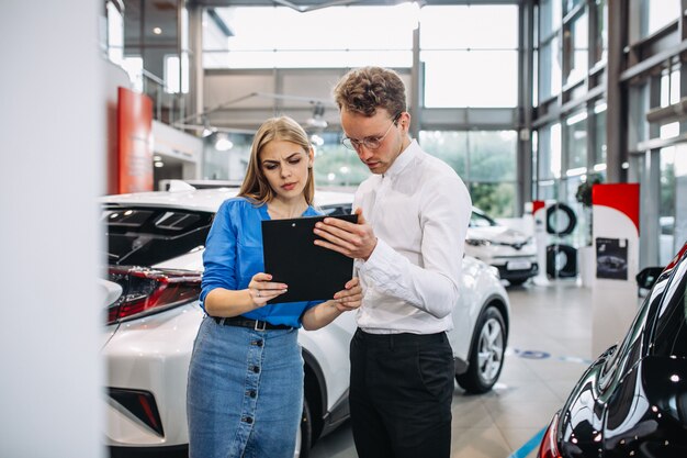 Frau, die ein Auto in einem Autosalon wählt