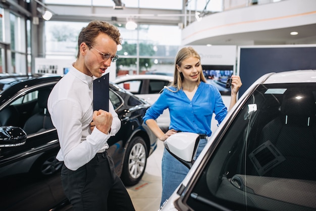 Frau, die ein Auto in einem Autosalon wählt