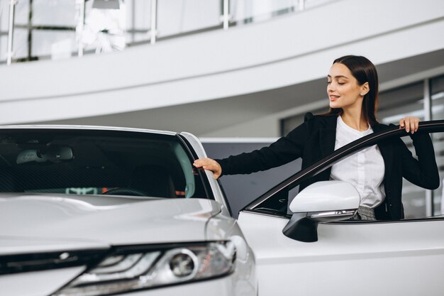 Frau, die ein Auto in einem Autosalon wählt