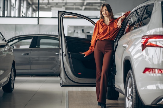 Frau, die ein Auto in einem Autosalon wählt