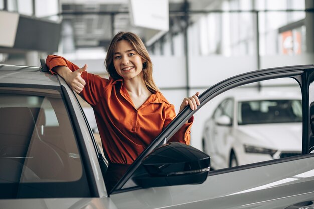 Frau, die ein Auto in einem Autosalon wählt