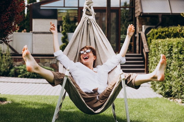 Kostenloses Foto frau, die ein buch im garten durch das haus liest