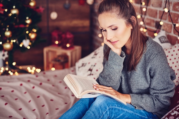 Frau, die ein Buch im Schlafzimmer liest