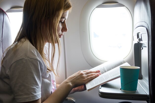 Frau, die ein Buch in einem Flugzeug liest