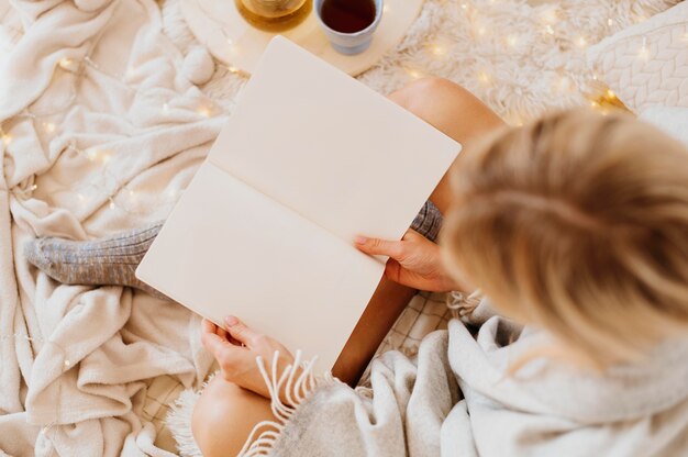 Frau, die ein Buch liest, während sie die Winterferien genießt