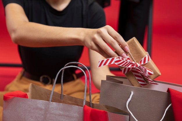 Frau, die ein eingewickeltes Geschenk in eine Einkaufstaschennahaufnahme einsetzt