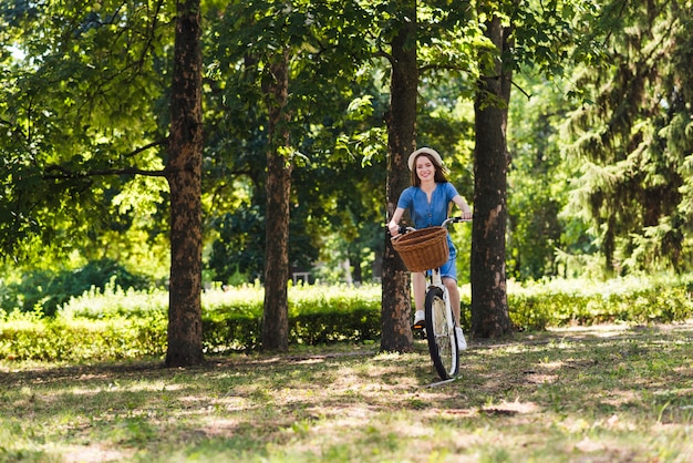 Frau, die ein Fahrrad auf Waldweg reitet
