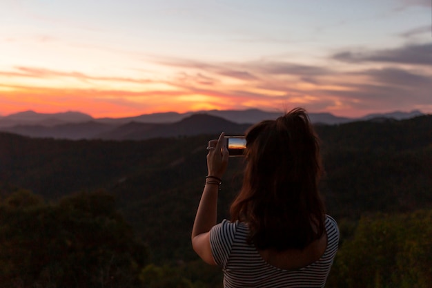 Frau, die ein Foto einer schönen Naturlandschaft macht