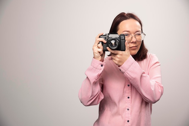 Frau, die ein Foto mit Kamera auf Weiß macht. Foto in hoher Qualität