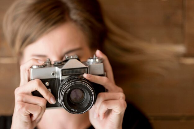 Frau, die ein Foto mit Retro-Kamera-Nahaufnahme macht