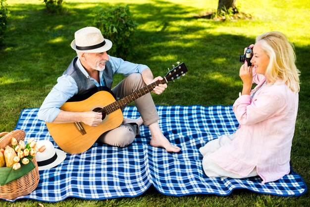 Frau, die ein Foto seines Mannes mit einer Gitarre macht