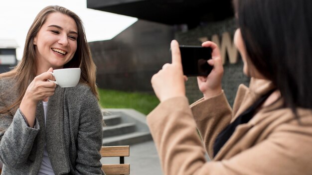 Frau, die ein Foto von ihrem Freund hält, der eine Tasse Kaffee hält