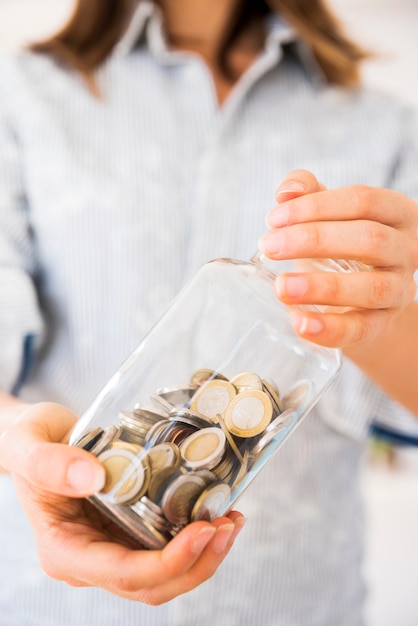 Frau, die ein Glas mit Geld hält