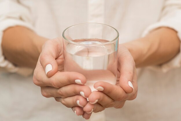 Frau, die ein Glas mit Wasser gefüllt hält