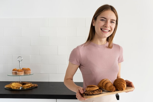 Kostenloses Foto frau, die ein hölzernes brett mit gebäck hält