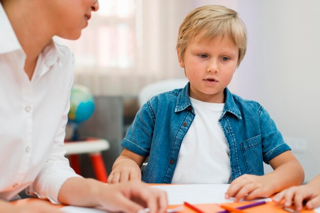 Frau, die ein Kind in der Klasse etwas unterrichtet