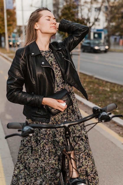 Kostenloses Foto frau, die ein langes kleid hält, das ihre fahrradvoransicht hält