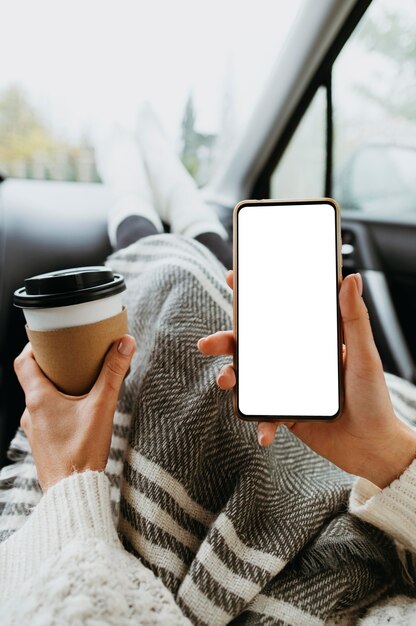 Frau, die ein leeres Telefon und eine Tasse Kaffee hält