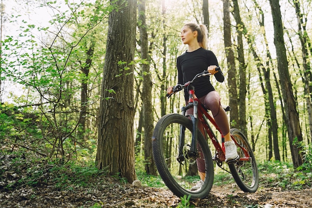 Kostenloses Foto frau, die ein mountainbike im wald reitet