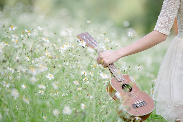 Frau, die ein nettes weißes kleid mit einem ukelele trägt