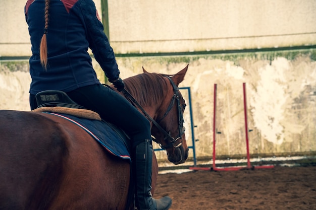 Frau, die ein pferd reitet, das von hinten geschossen wird