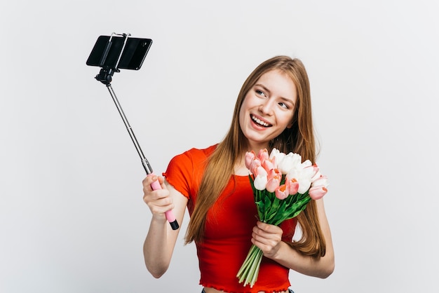 Frau, die ein selfie beim Halten eines Blumenstraußes der Tulpen nimmt