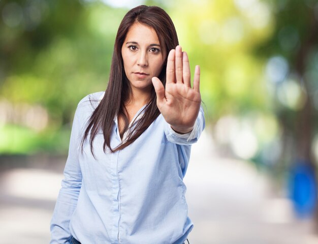 Frau, die ein Stop-Schild mit einer Hand