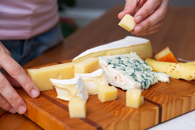 Frau, die ein Stück Käse vom Holzbrett nimmt
