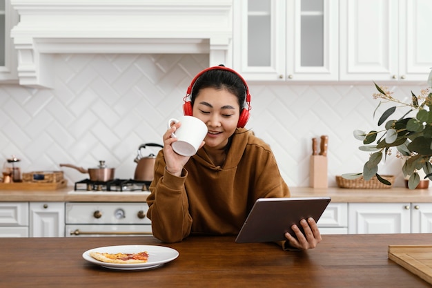 Kostenloses Foto frau, die ein video auf tablette betrachtet und kaffee trinkt