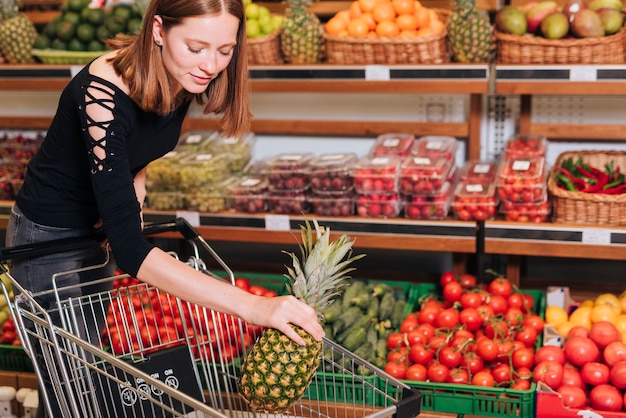 Frau, die eine Ananas in den Wagen einsetzt