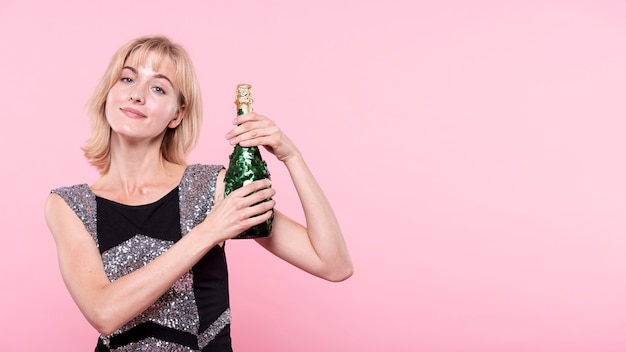 Frau, die eine Flasche Champagner auf rosa Hintergrund zeigt