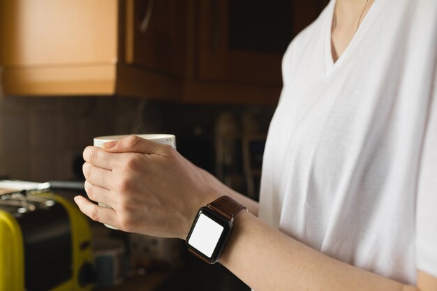 Frau, die eine Kaffeetasse in der Küche hält