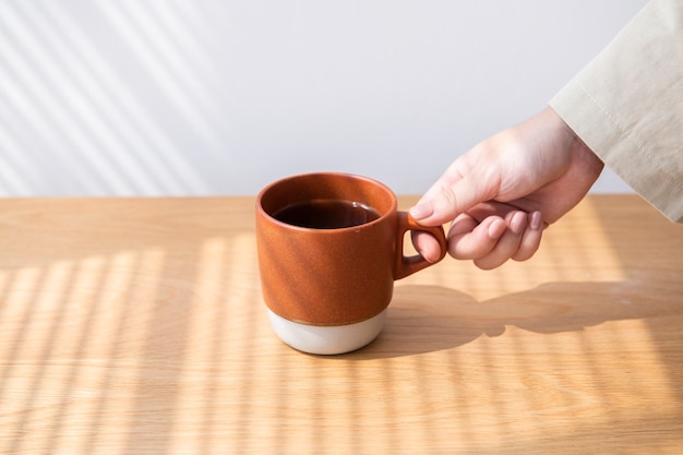 Frau, die eine Kaffeetasse von einem Holztisch erhält