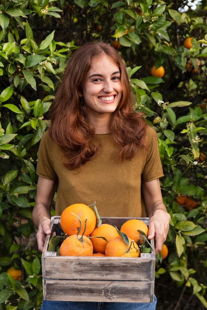 Frau, die eine Kiste voller Orangen in den Händen hält