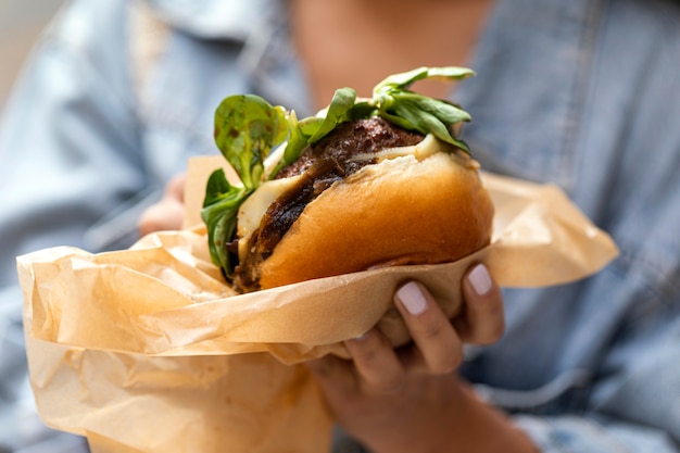 Kostenloses Foto frau, die eine köstliche burger-nahaufnahme hält