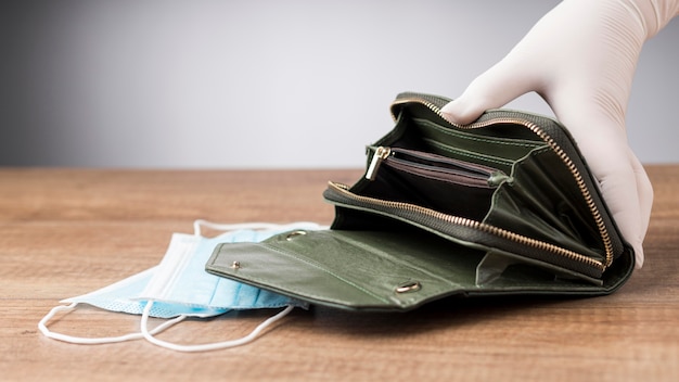 Frau, die eine leere Brieftasche neben einer Gesichtsmaske hält