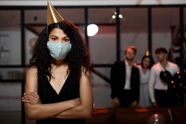 Frau, die eine medizinische Maske auf Silvesterparty mit Kopienraum trägt