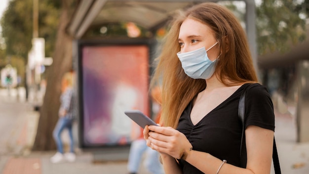 Kostenloses Foto frau, die eine medizinische maske draußen trägt