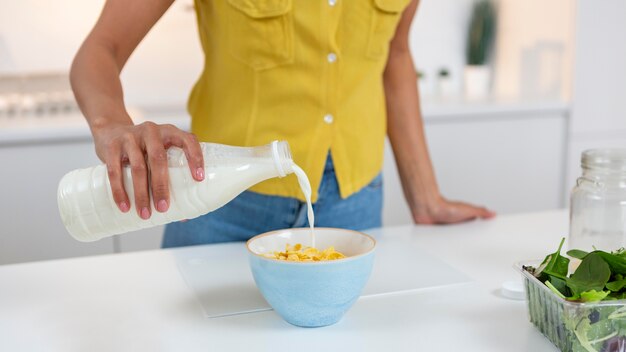 Frau, die eine Schüssel Müsli mit Milch vorbereitet