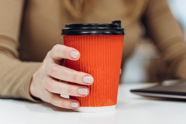 Frau, die eine tasse kaffee bei der arbeit hält