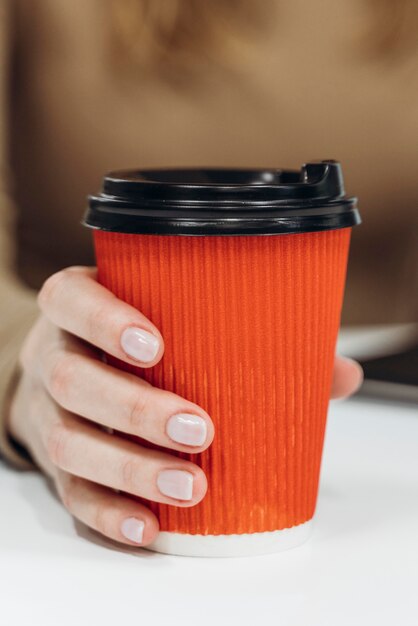 Frau, die eine Tasse Kaffee bei der Arbeit Nahaufnahme hält