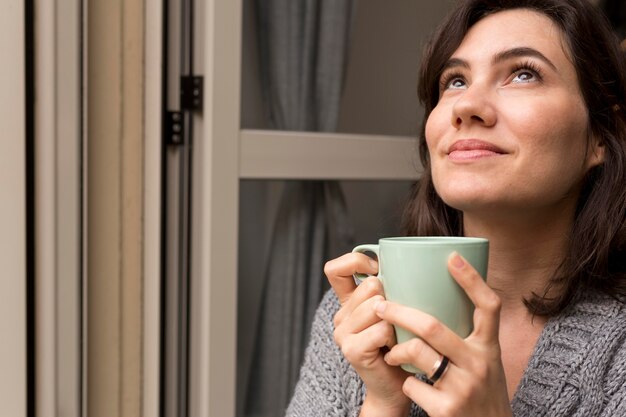 Frau, die eine Tasse Kaffee beim Aufschauen hält