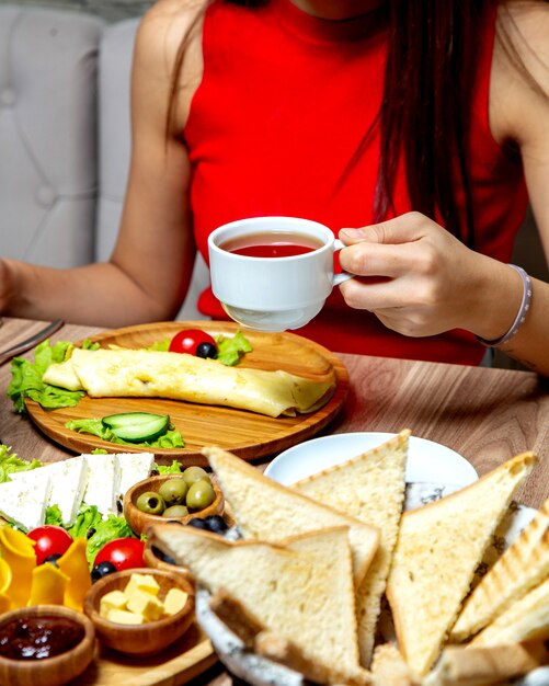 Frau, die eine Tasse schwarzen Tee trank, diente zum Frühstück