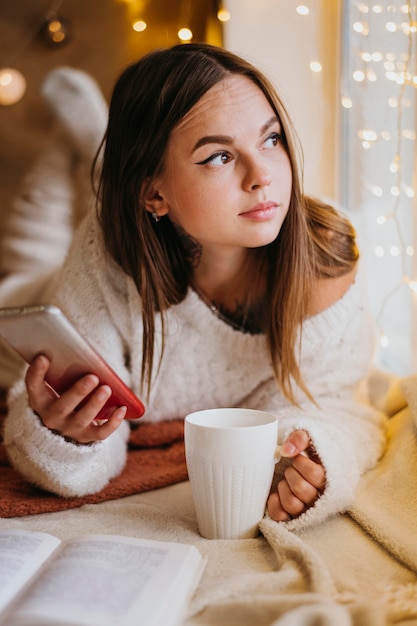 Kostenloses Foto frau, die eine tasse tee hält, während sie wegschaut