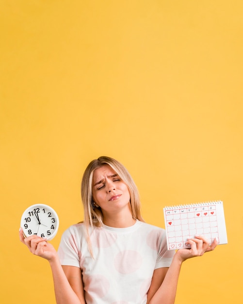 Frau, die eine Uhr und einen Monatskalenderkopienraum hält